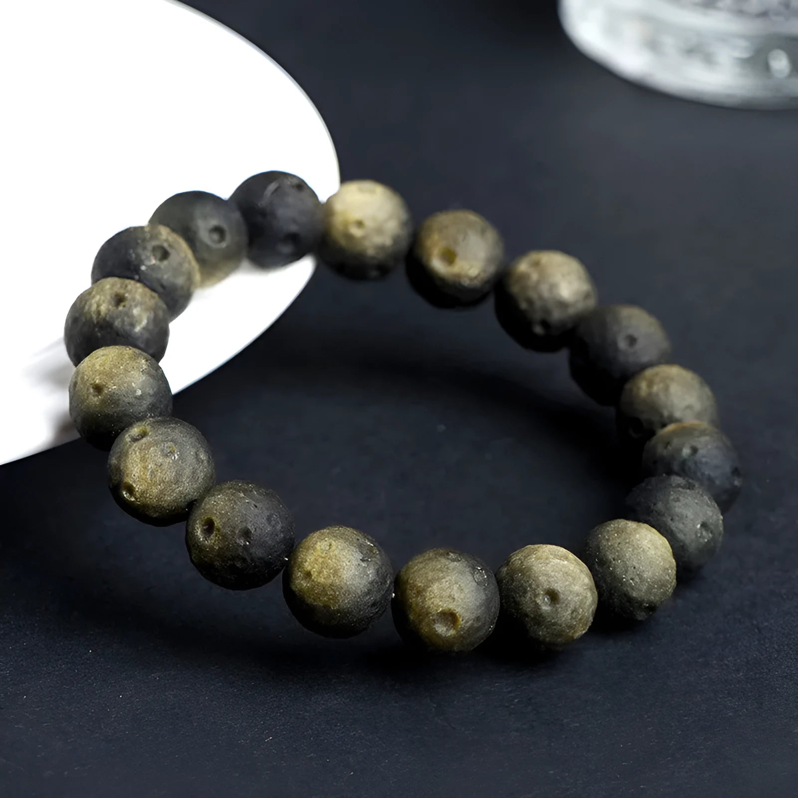 Natural obsidian crater ball bracelet with textured beads in silver stone meteorite colour on a wrist.