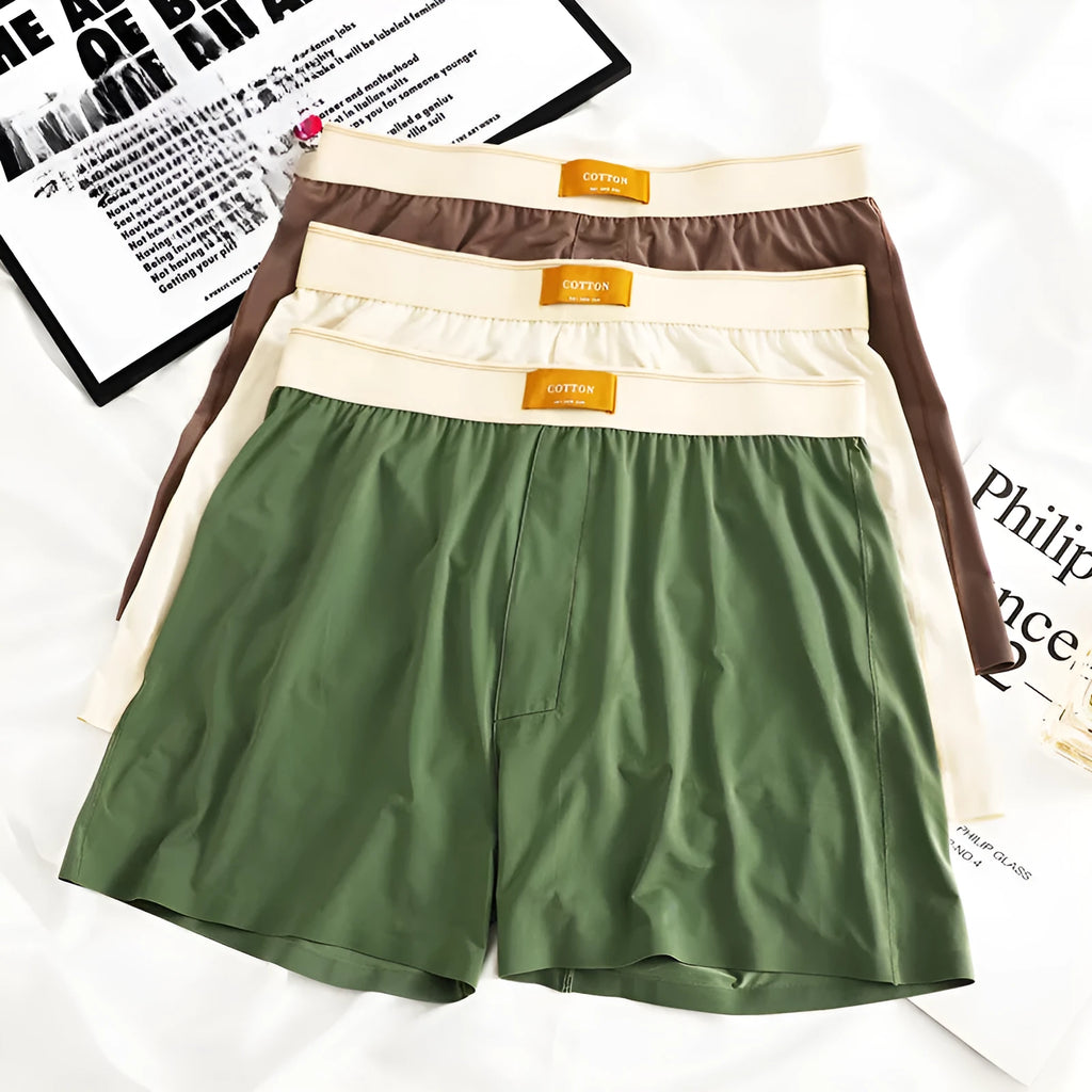 Pack of three men's loose fit ice silk boxer shorts in solid colours on a mid-waist model.