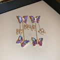 A pair of blue purple butterfly tassel drop earrings with crystal flowers and silver needle details on alloy.