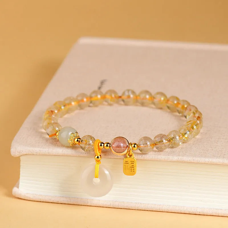 Gold rutilated quartz crystal bracelet with safety buckle and geometric national style design featuring blessing card pendant.