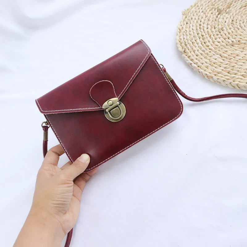 Soft surface PU messenger bag in wine red with a flap closure and metal lock detail.