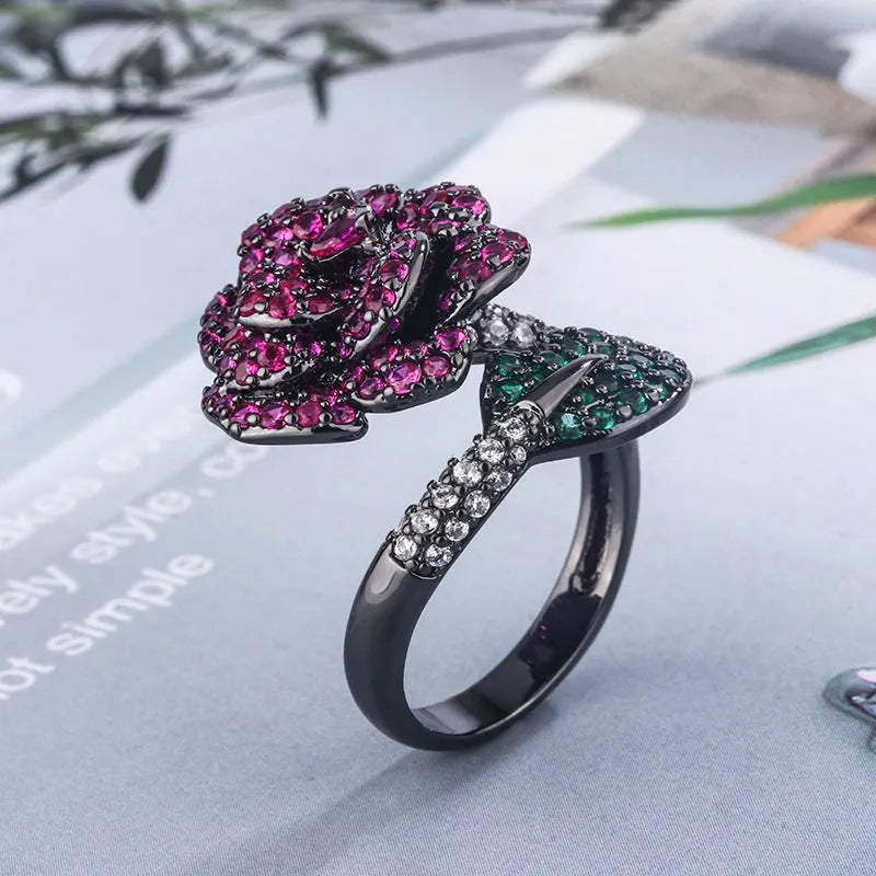 Geometric black gold plated ring with red simulated corundum stone in a floral setting.
