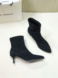 Black pointed toe women's ankle boots with a stiletto heel and mid-calf sock length on a white background