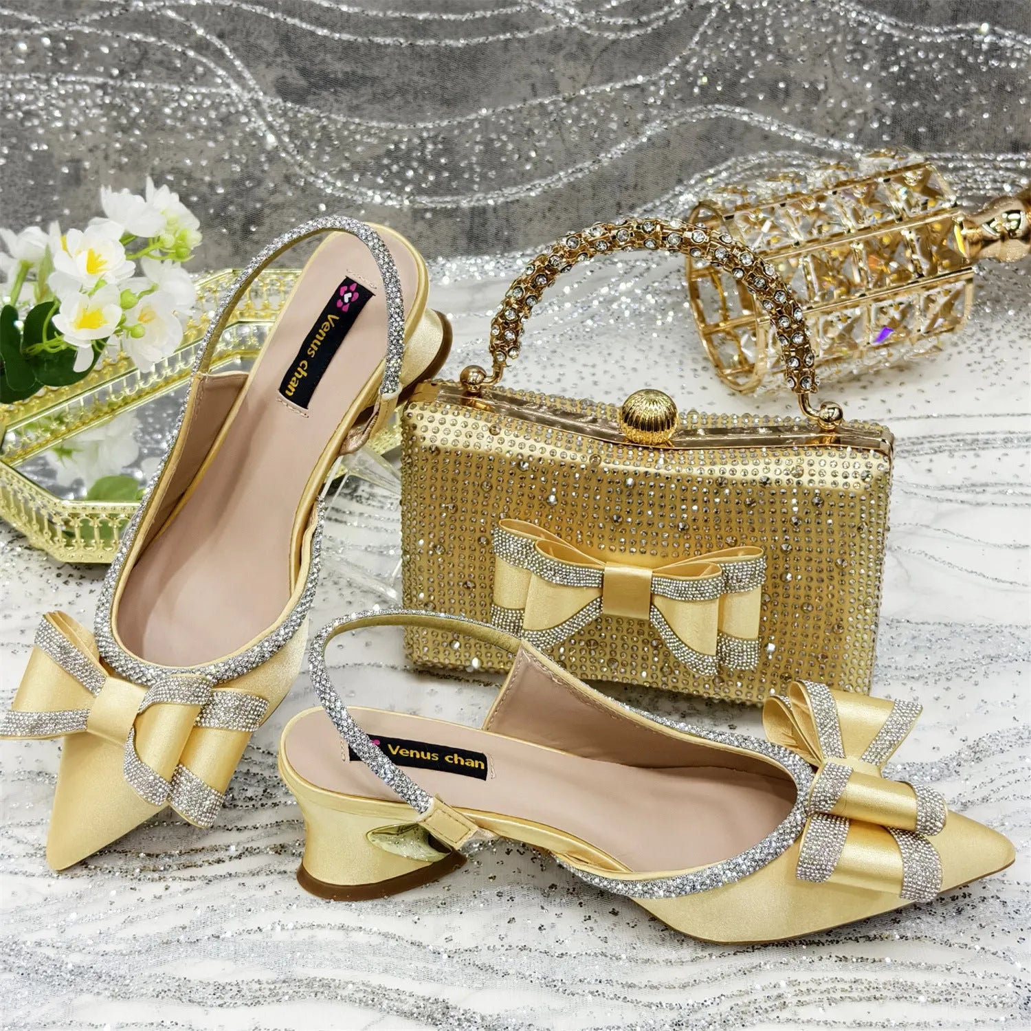 Women's pointed toe sandals with a square rhinestone buckle and a matching bag on a mid heel