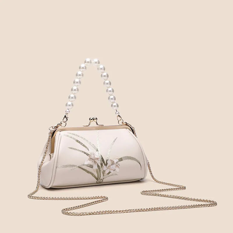 Beige women's shoulder bag with embroidered detailing and a soft, shell-shaped design.