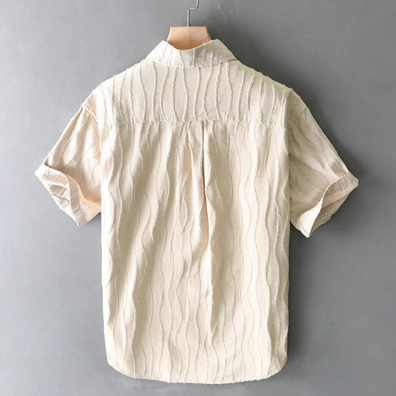 Man wearing a loose-fit pure cotton summer shirt in apricot colour against a light background.