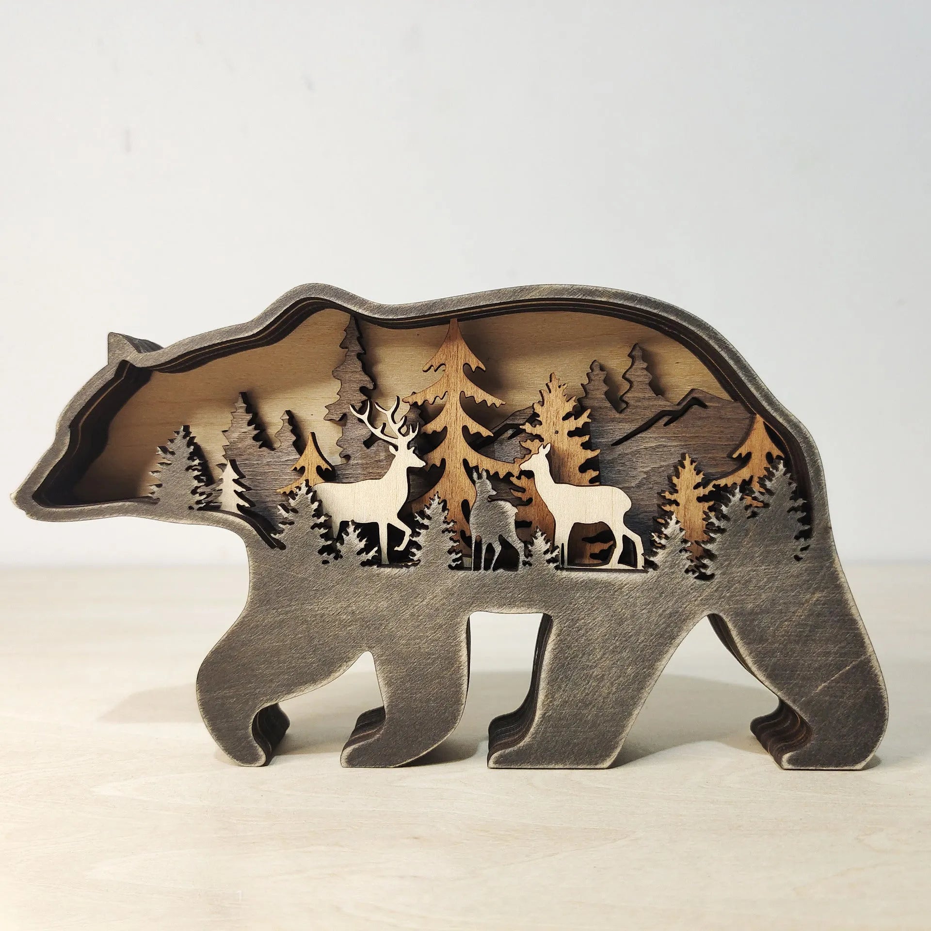 Two boxwood wooden ornaments, elk and brown bear, on a flat surface with natural wood finish