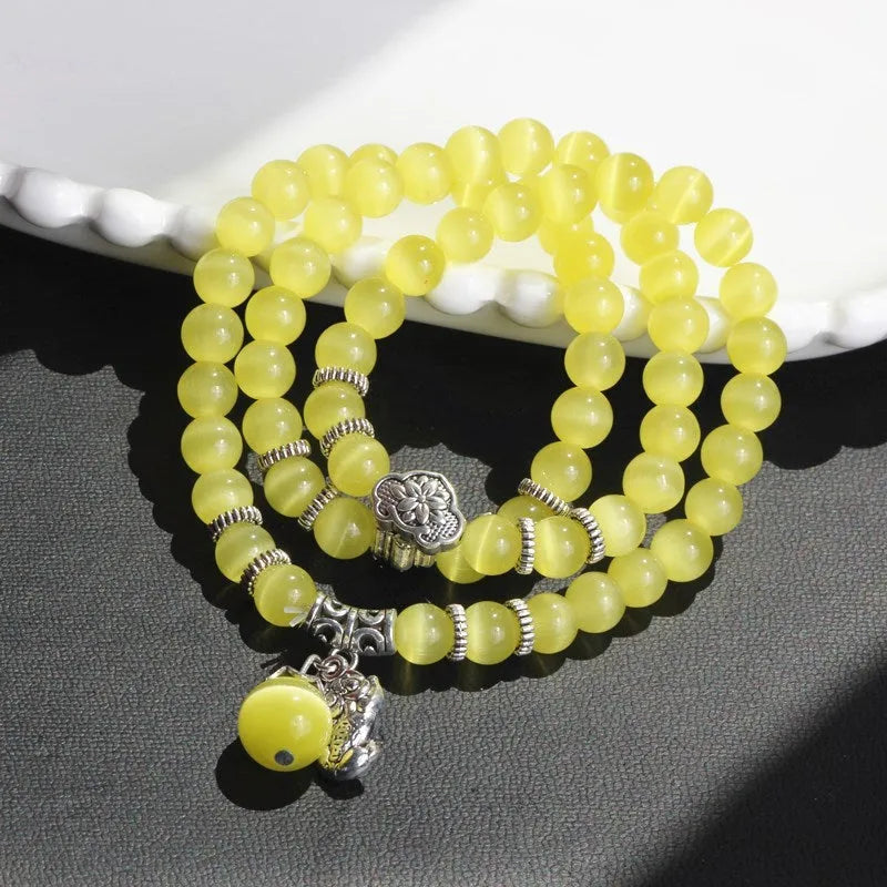 Women's opal bracelet with a Cat Eye charm, shown in one of six colours, wound three times around a wrist.