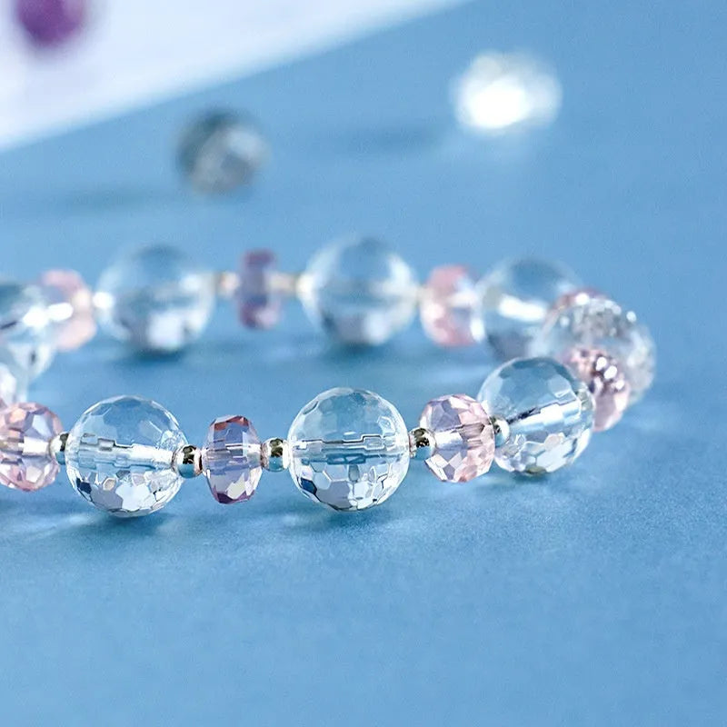 Women's white crystal bracelet with diamond shapes and lucky cat charm on wrist