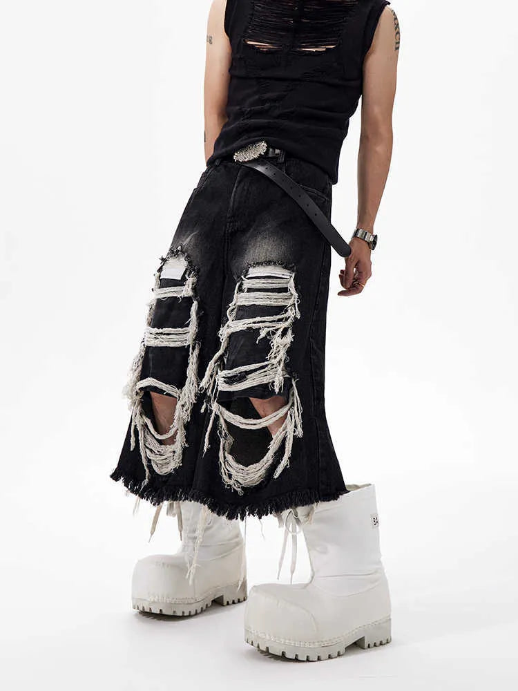 Woman wearing black distressed wide leg cropped jeans with ripped patches.