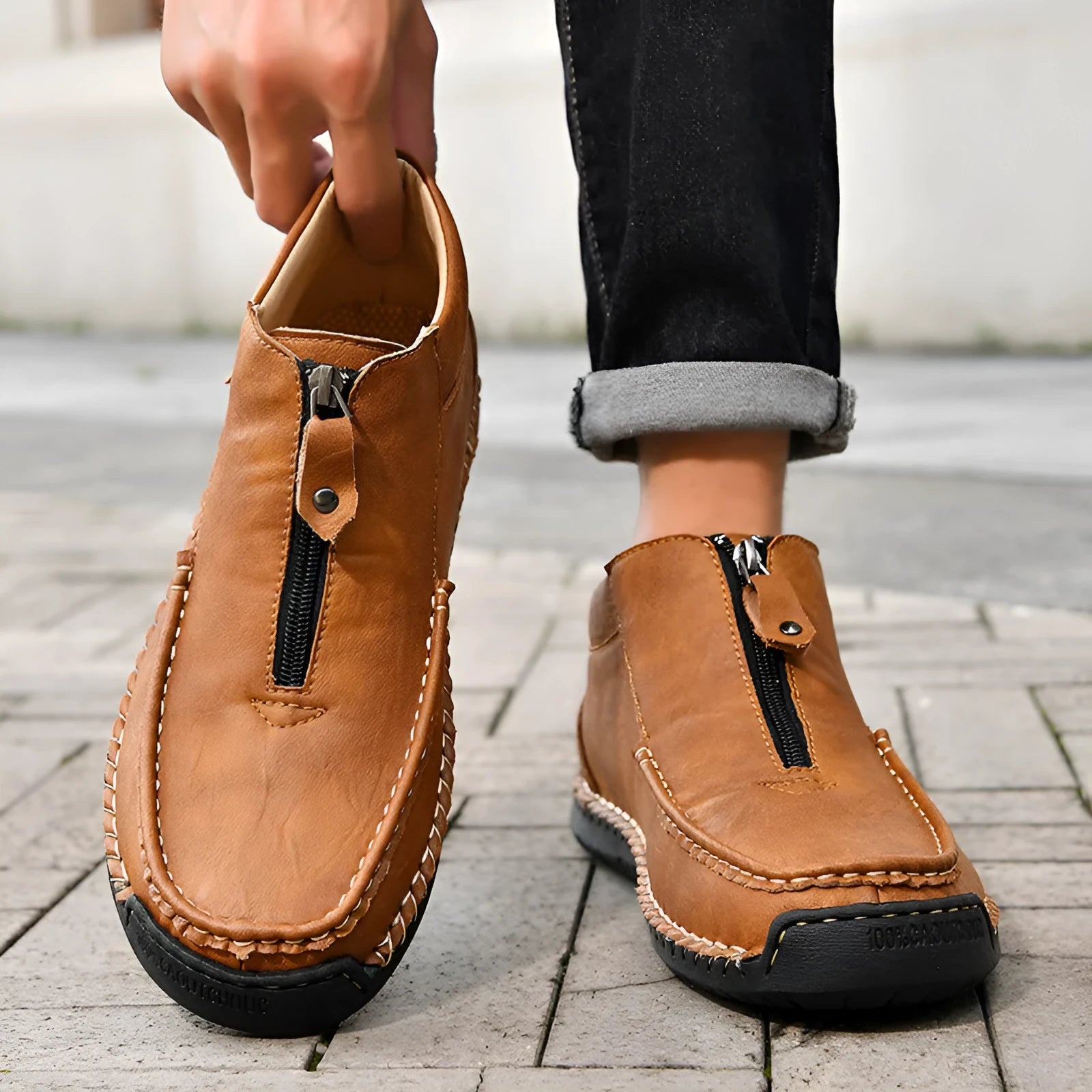 Men's black slip-on loafers with a round toe and sewn rubber sole on a grey background.
