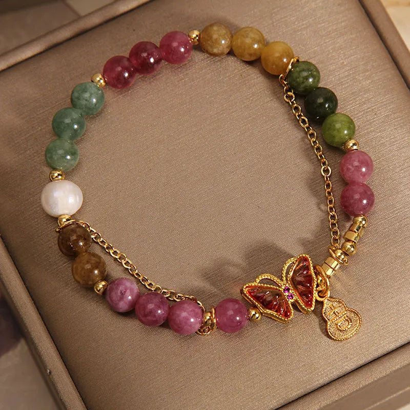 Close-up of a women's agate bracelet with a green tourmaline butterfly-shaped gourd charm on a white background.