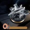 Silver solar-powered rotating fighter jet perfume ornament on a wooden surface.