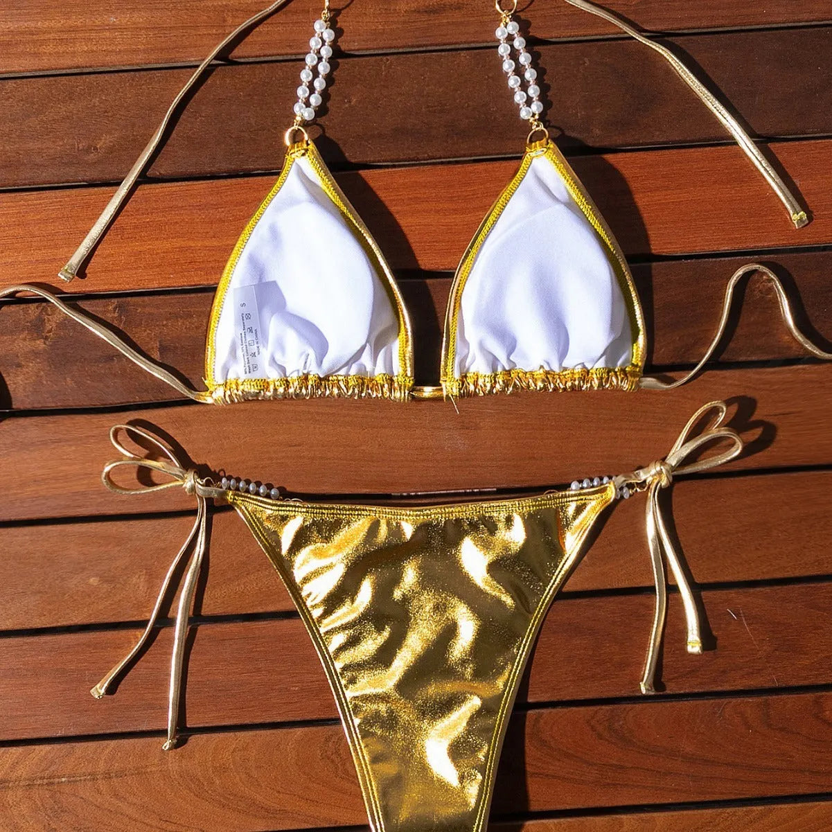 Gold halter neck bikini top with lace-up front and matching briefs, featuring pearl chain detail.