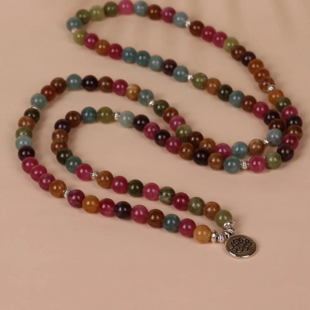 Close-up of a Tourmaline-coloured alloy bracelet with 108 beads and a central hanging lotus decoration.