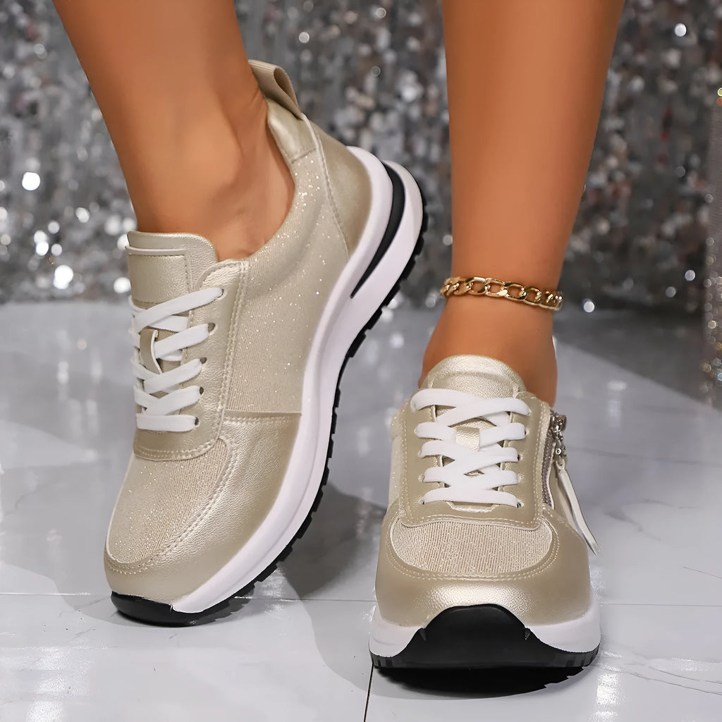 Gold women's flat lace-up pumps with round toe and rubber sole on a white background.