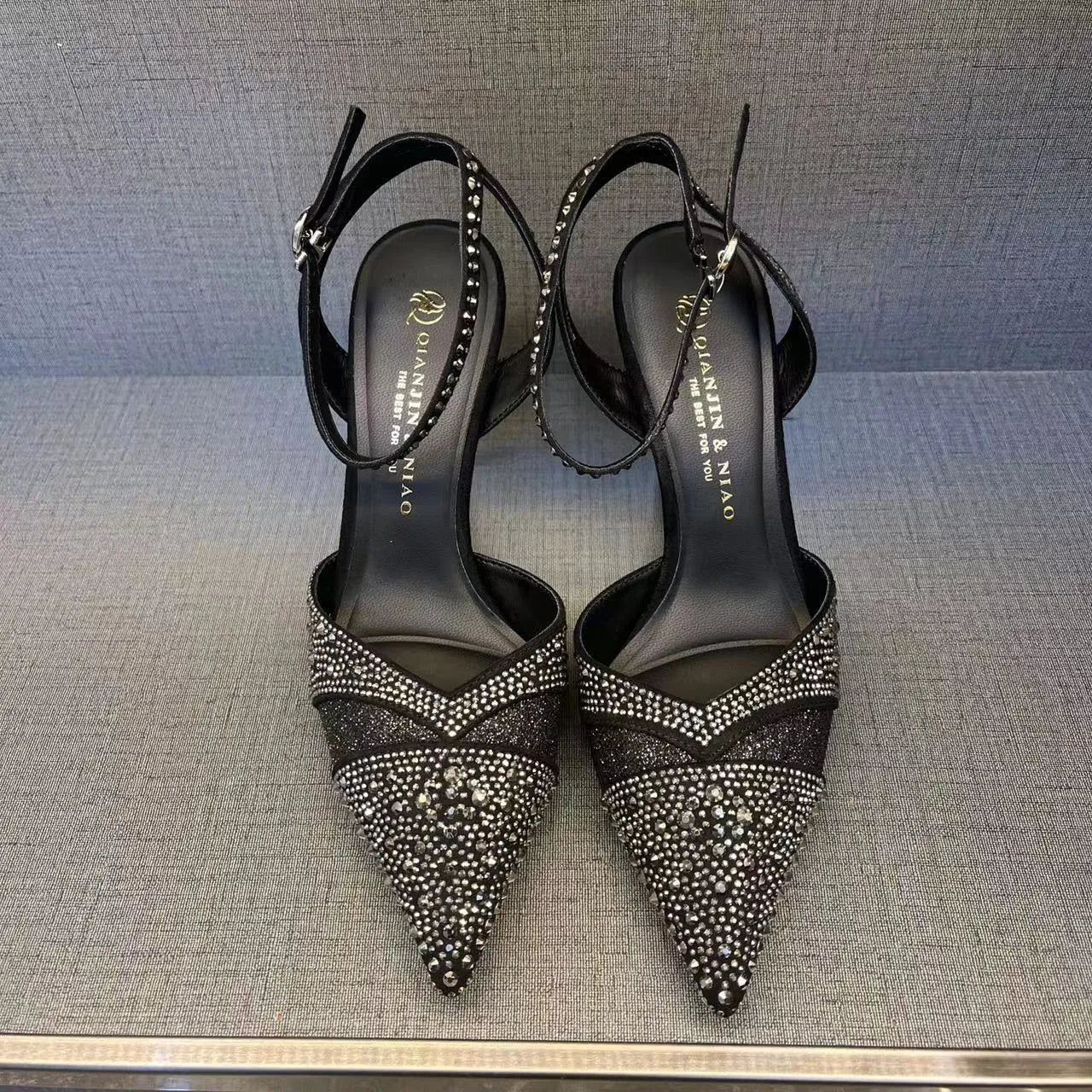 Women's black and silver hollow high heels with a red sole and pointed stiletto toe.