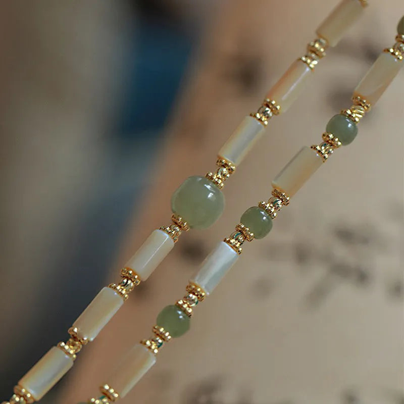 Simple women's bracelet made of round white Hetian jade beads on a wrist.