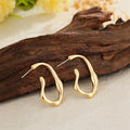Irregular shaped minimalist drop earrings in gold tone on a clean background