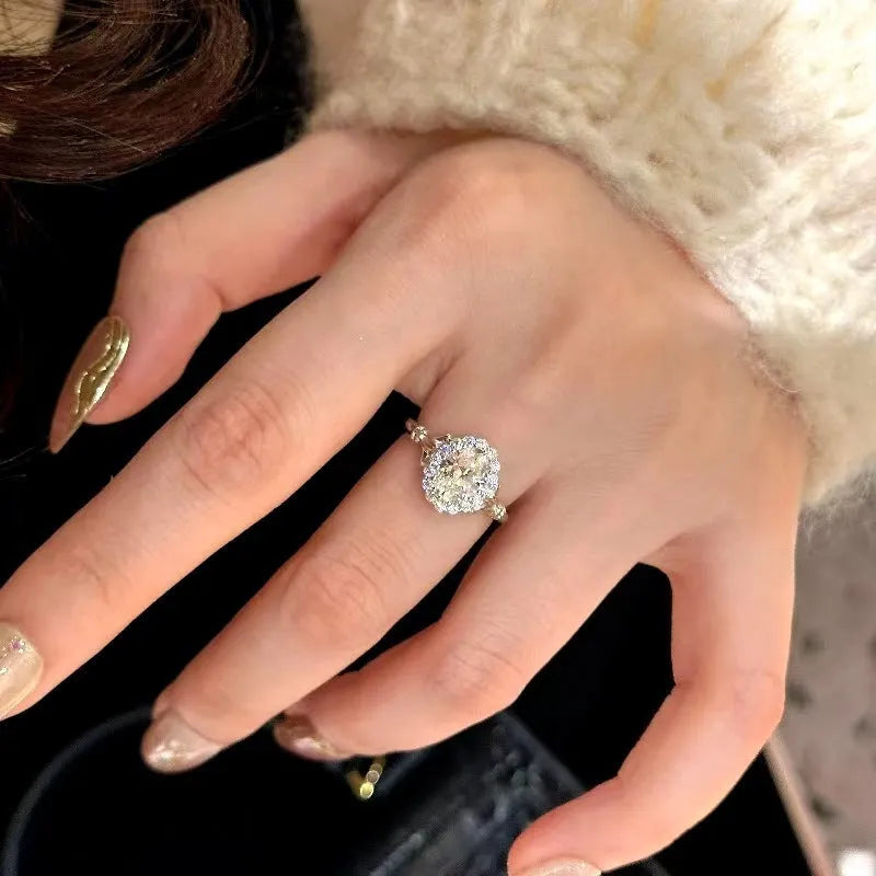 Silver geometric ring with a large diamond detail and adjustable opening on a woman's index finger.