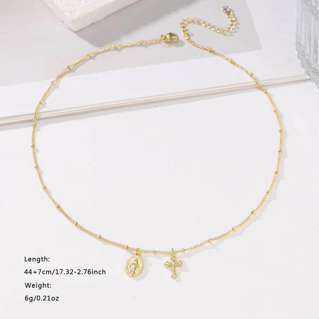 Gold geometric cross necklace with a Virgin Mary ornament pendant on a chain.