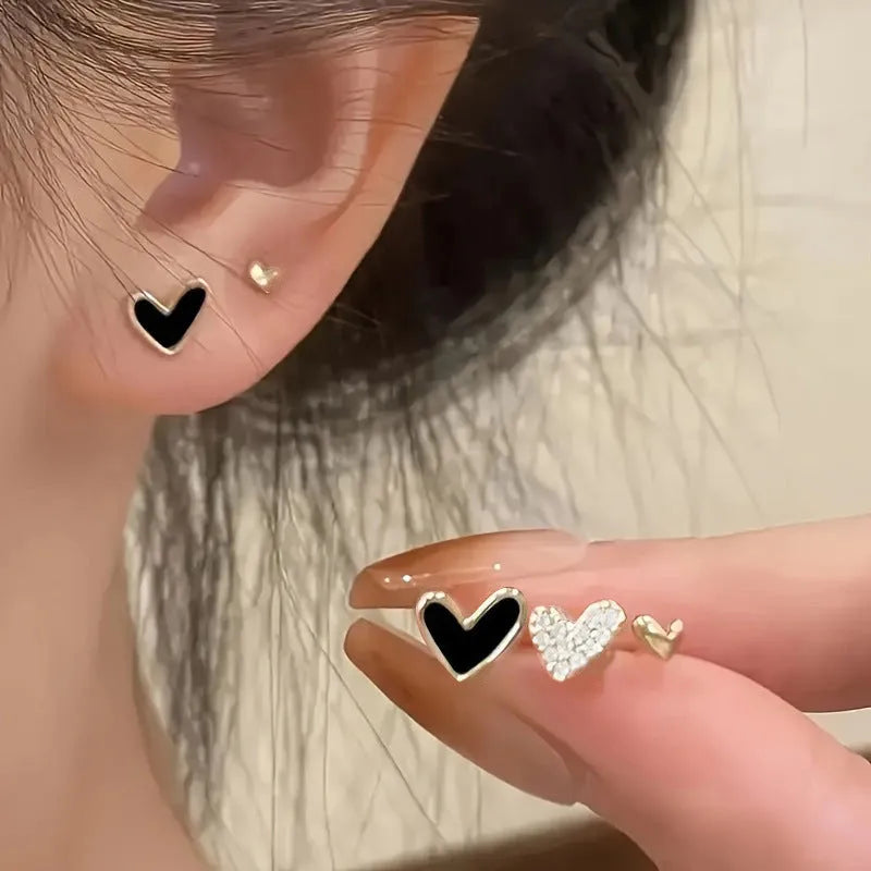 Three pairs of women's heart-shaped alloy earrings in electroplated colours on display