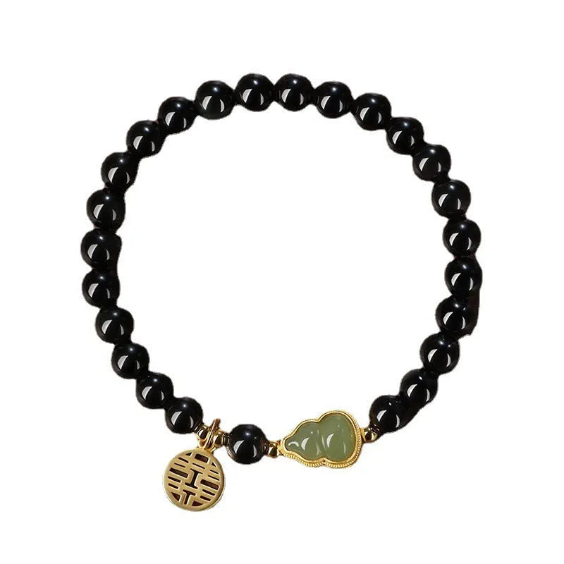 Black obsidian bracelet with carved Hetian jade gourd charm showing geometric patterns