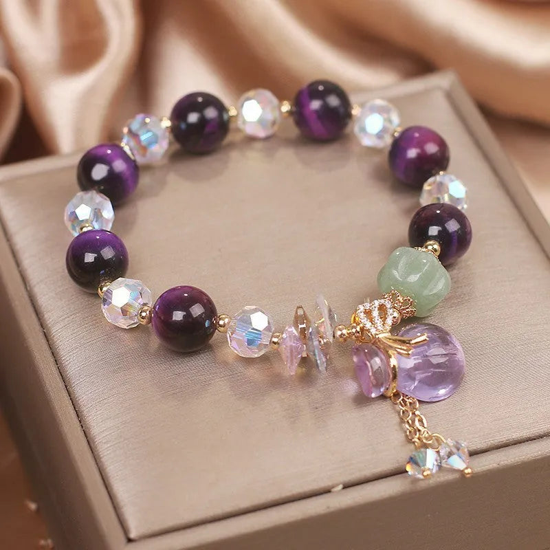 Women's purple Tigereye pendant crystal bracelet with rhinestones on a forest-style background.