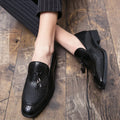 Men's black pointed slip-on business shoes with a tassel detail on the artificial PU leather upper.