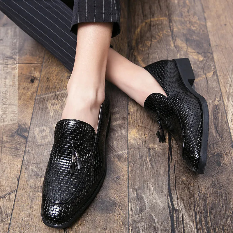 Men's black pointed slip-on business shoes with a tassel detail on the artificial PU leather upper.