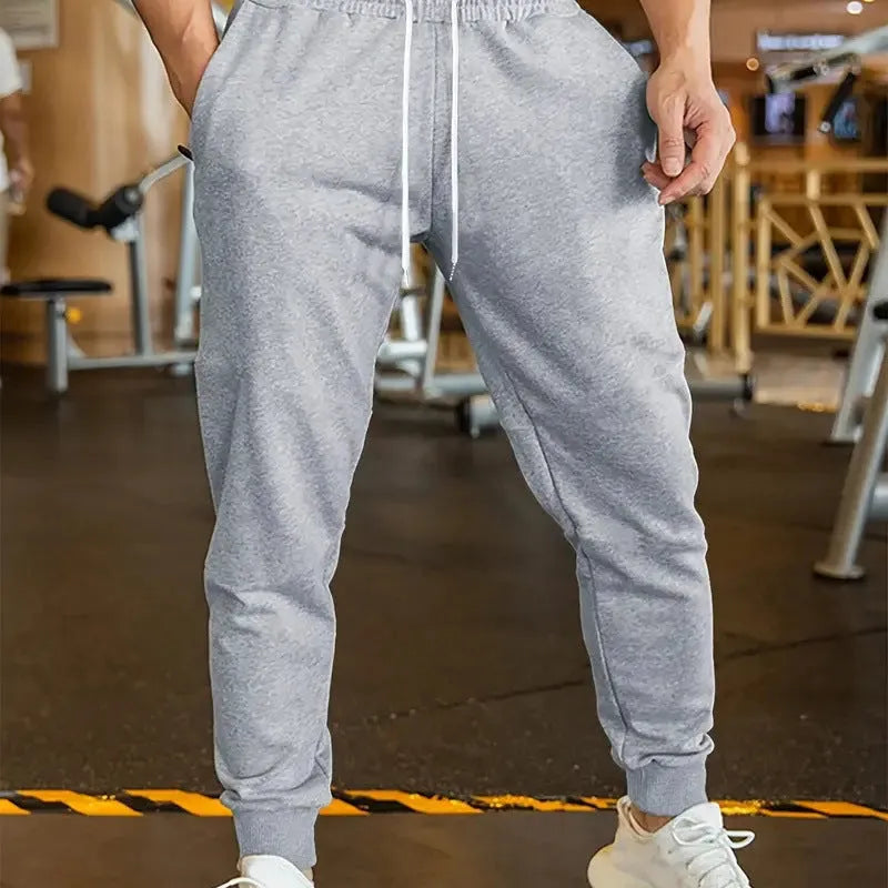 Man wearing grey loose-fit linen-style leisure trousers with an elastic drawstring waistband.