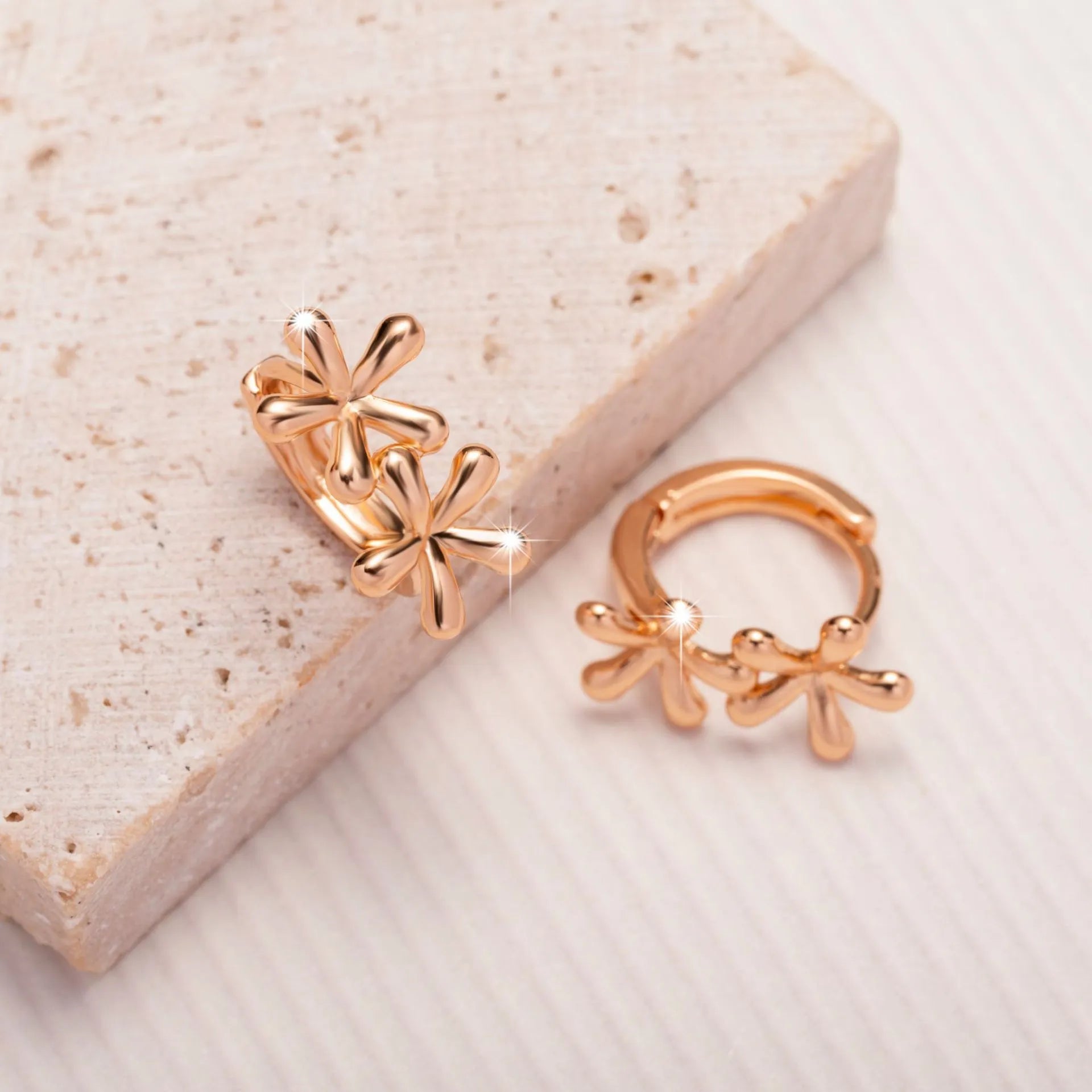 A pair of rose gold coloured waterdrop and circular shaped women's earrings on a white background.