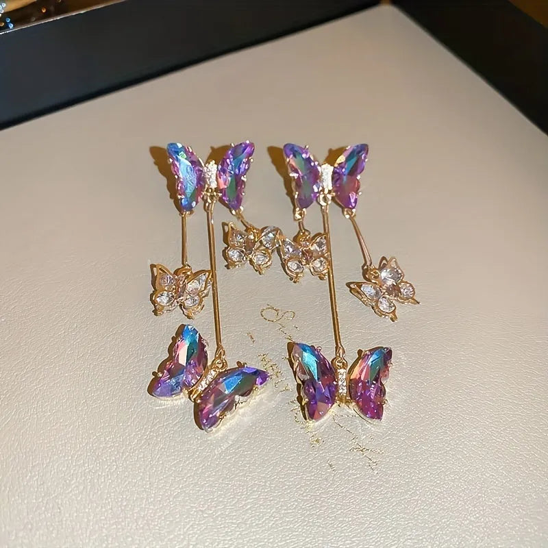 A pair of blue purple butterfly tassel drop earrings with crystal flowers and silver needle details on alloy.