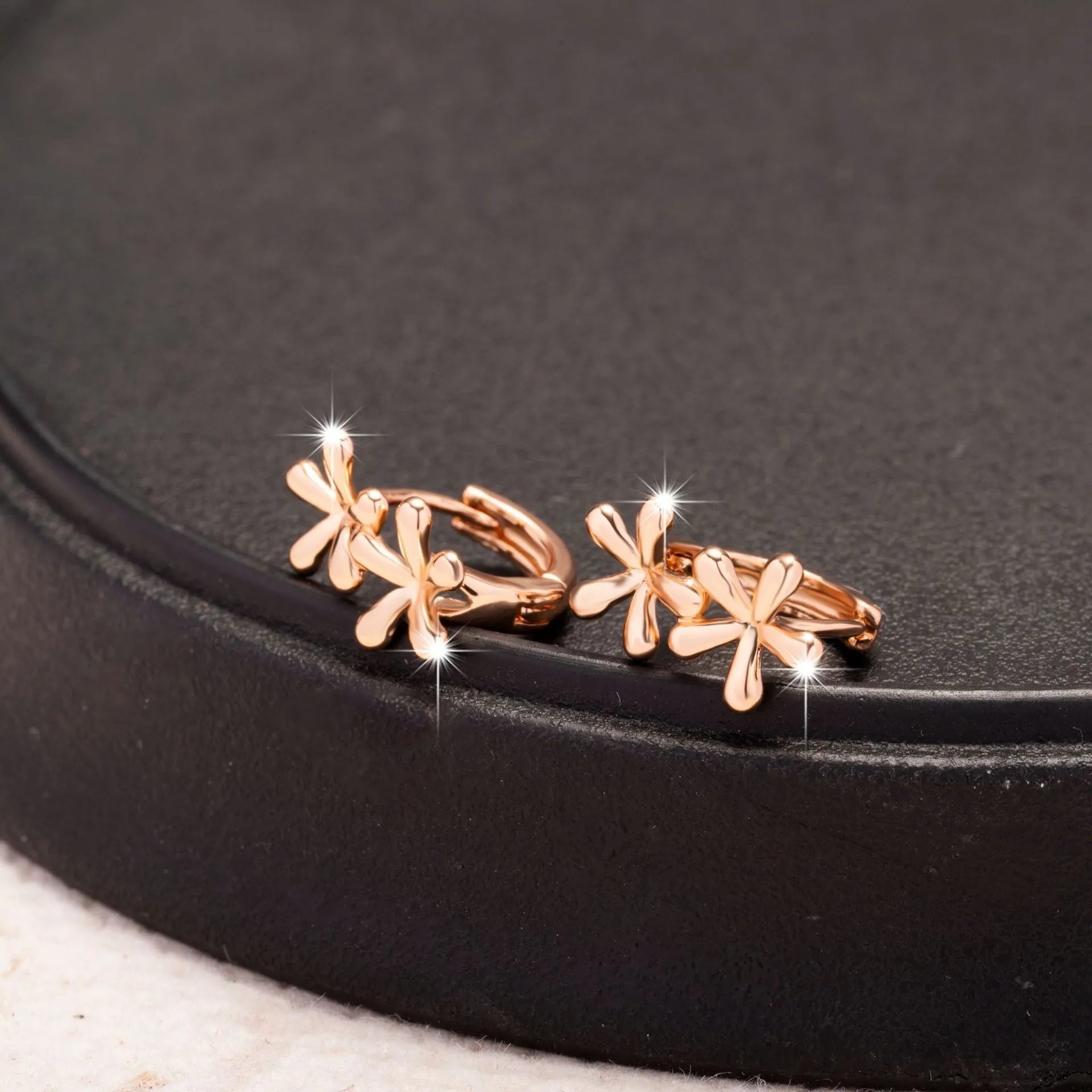 A pair of rose gold coloured waterdrop and circular shaped women's earrings on a white background.