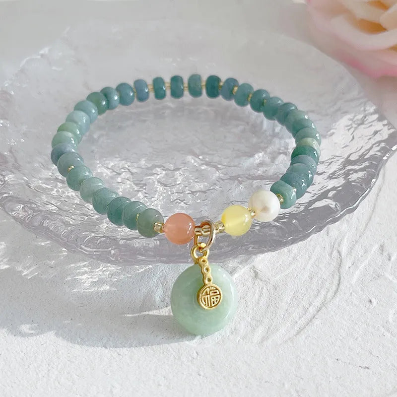 Women's jade bracelet with gourd shape, peace buckle charm, and strawberry quartz details in natural blue colours