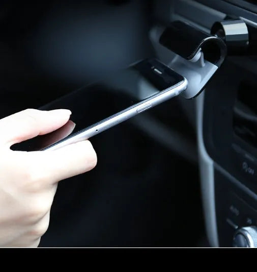 Black universal car phone holder with 360-degree rotating head on a car dashboard.