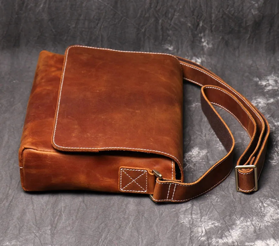 Vintage brown cowhide men's messenger bag showing front flap and adjustable shoulder strap