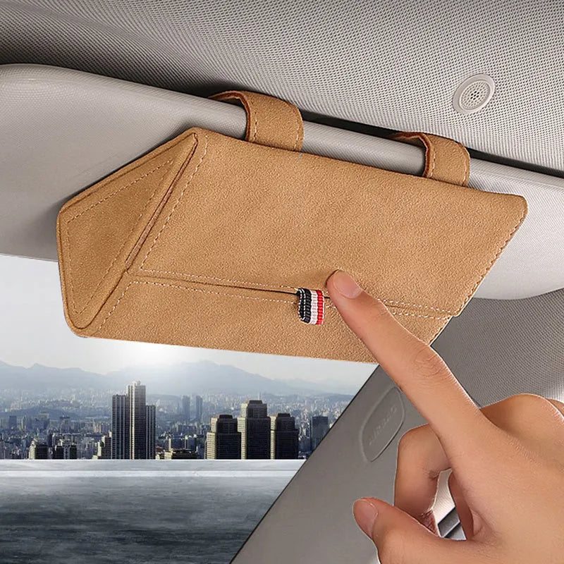 Suede car glasses storage box in beige attached to car sun visor holding sunglasses and phone