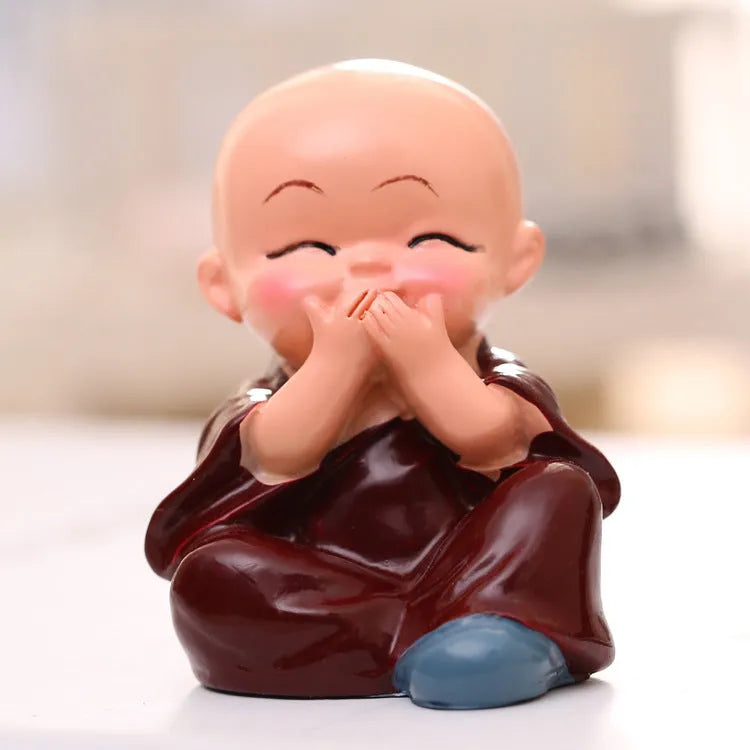 Set of 4 miniature resin Buddha monk statues in blue, brown, gray, and orange, 4.7 cm tall, on a shelf