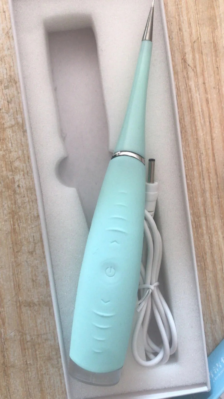 Pink and blue electric dental scaler tool with silicone handle on a bathroom counter.