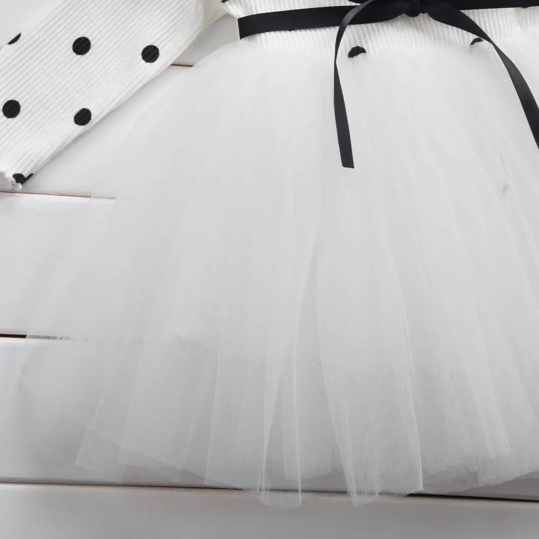 Baby girl in a long sleeve white lace tutu dress for a christening or birthday party.