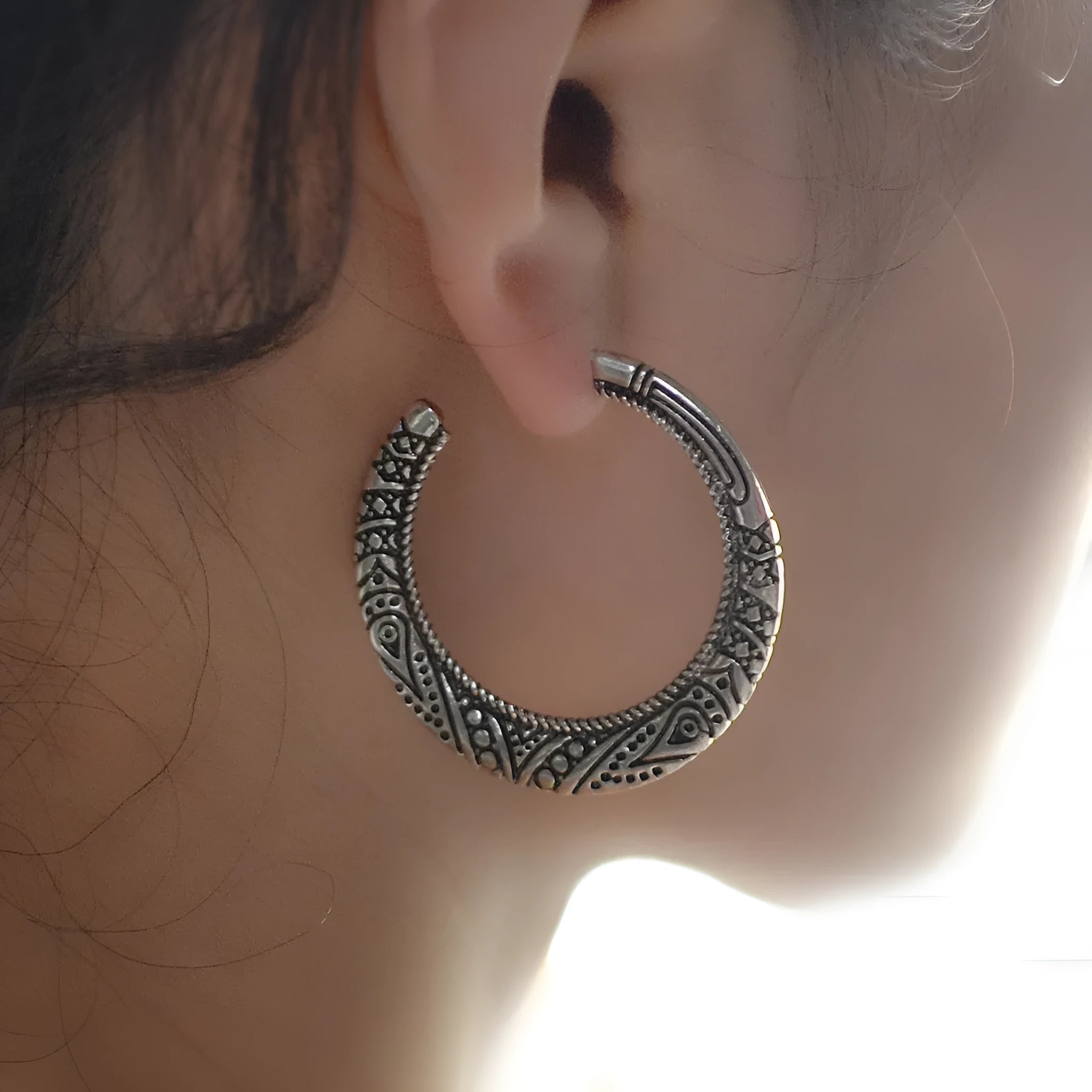 Pair of vintage engraved C-shaped alloy earrings in bronze finish, showing detailed etching.