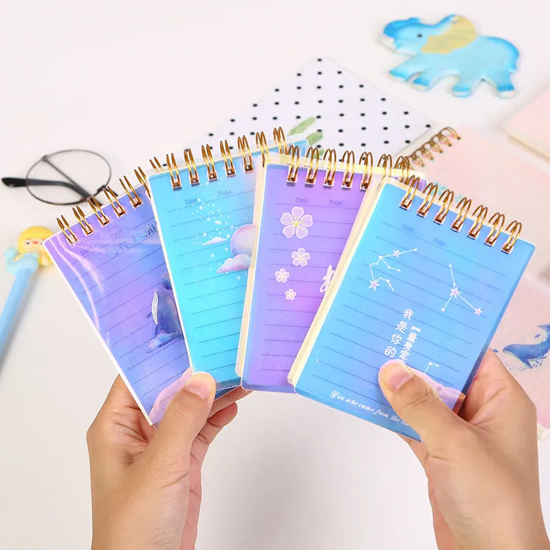 Set of four A7 spiral-bound pocket notebooks with rollover coils, showing Constellation, Sakura, Ocean, and Universe cover designs.