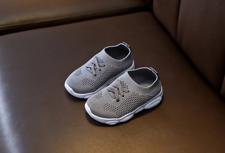 Children's fabric lazy shoe with a non-slip rubber sole, shown in colour options of white, black, pink, and grey.
