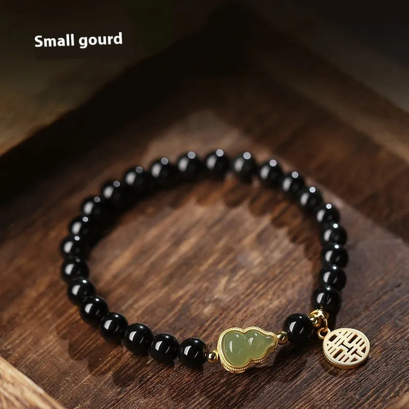 Black obsidian bracelet with carved Hetian jade gourd charm showing geometric patterns