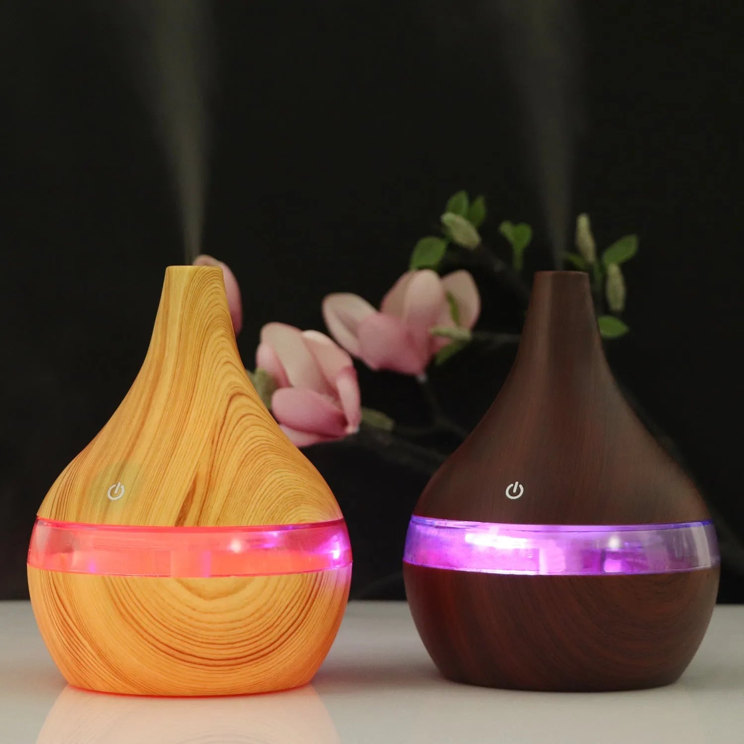 A columnar USB air humidifier with a wood grain finish, remote control, and USB cable on a desktop.