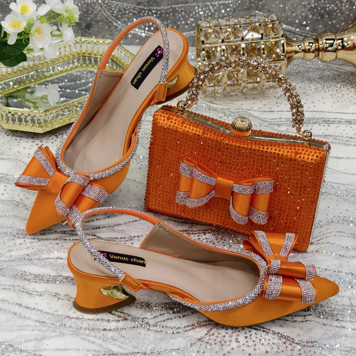 Women's pointed toe sandals with a square rhinestone buckle and a matching bag on a mid heel