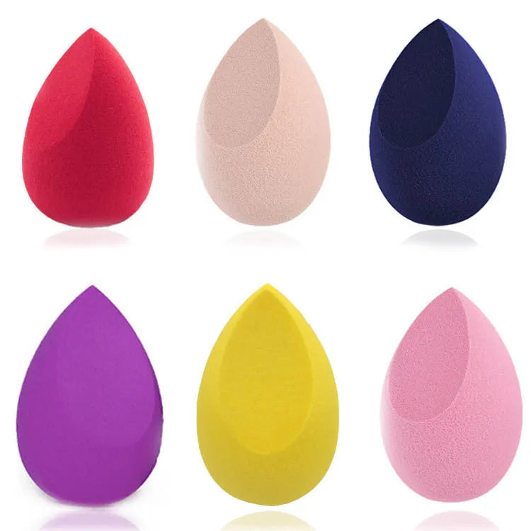 Set of seven differently shaped makeup sponges in various colours on pink background