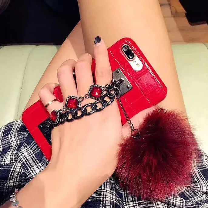 Red iPhone case with rhinestone decoration and attached fox fur ball showing Japanese Korean style design