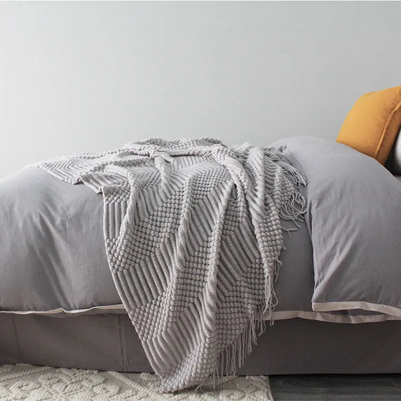Small light grey polyester throw blanket folded on a sofa, showing its compact 127x170cm size.
